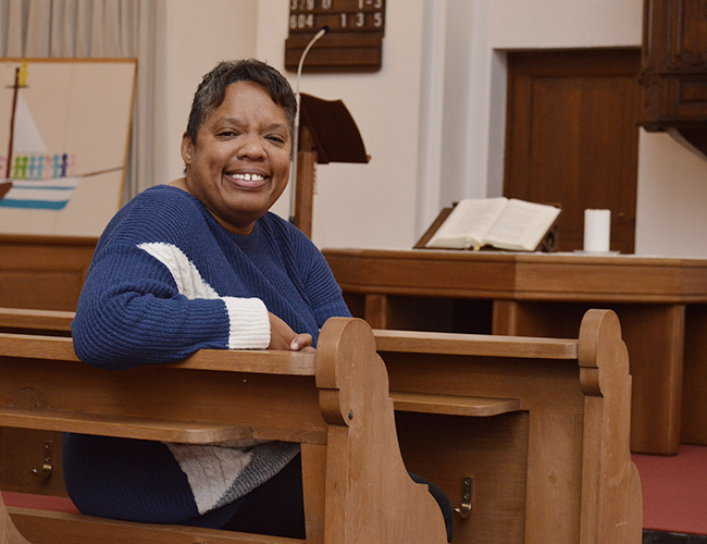Claudette Williams sitzt auf einer Kirchenbank in der evangelischen Kirche in Roetgen
